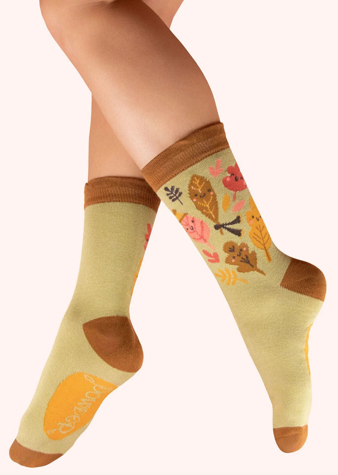 Colorful socks with autumn-themed design worn by a person on a white background